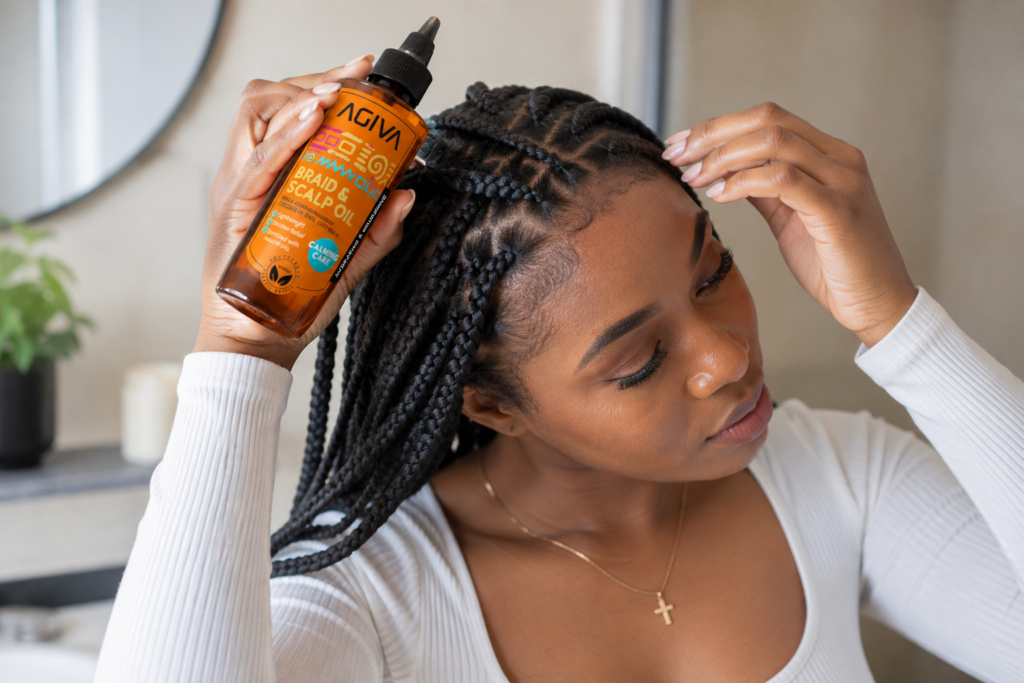 Woman applying AGIVA Braid & Scalp Oil to moisturize her scalp while wearing braids.